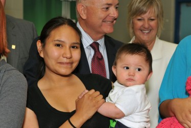 Mom Labrina holds her baby Malias. Behind her are Phil Klein, VP commercial fina